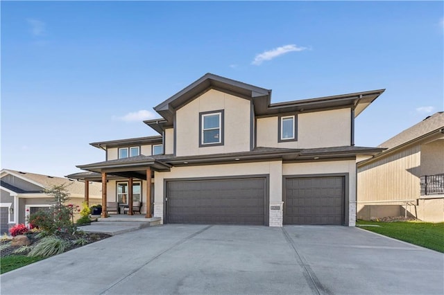 prairie-style house with a garage, driveway, and stucco siding