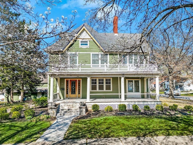 victorian-style house with a front yard, covered porch, and a chimney