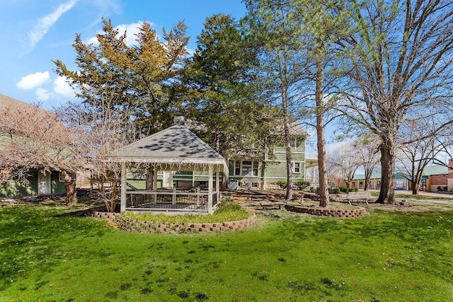 back of property with a yard and a gazebo