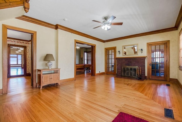 unfurnished living room featuring light wood-type flooring, a brick fireplace, visible vents, and crown molding