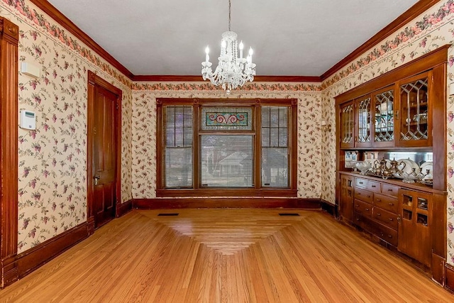 unfurnished dining area with parquet floors, a notable chandelier, baseboards, and wallpapered walls