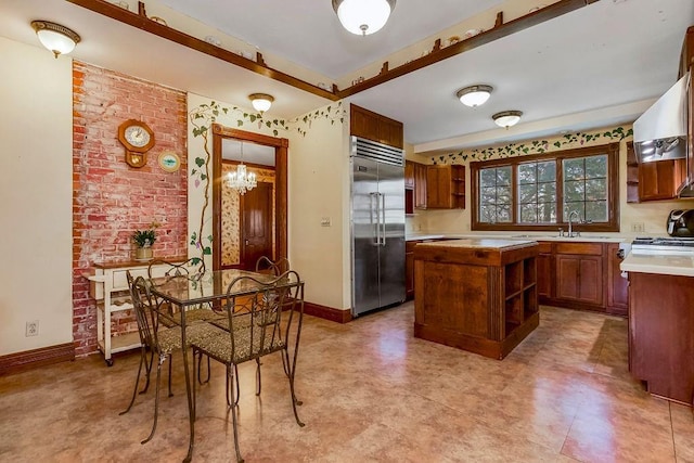 kitchen featuring built in fridge, a center island, open shelves, light countertops, and a sink