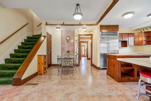 kitchen with built in fridge, visible vents, light countertops, open shelves, and brown cabinetry