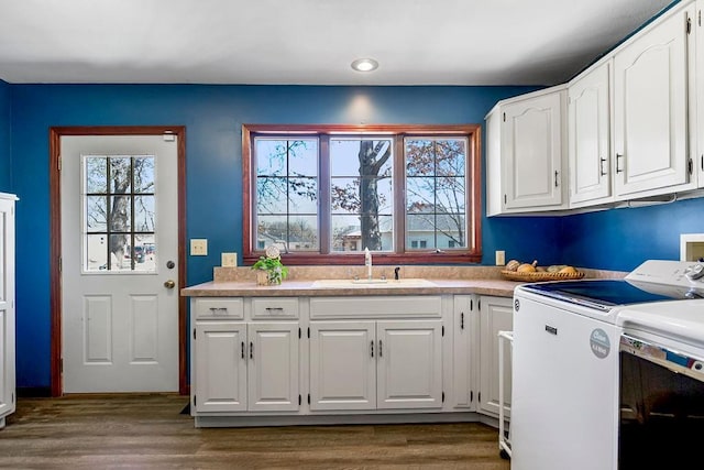 kitchen featuring wood finished floors, separate washer and dryer, a sink, and white cabinets