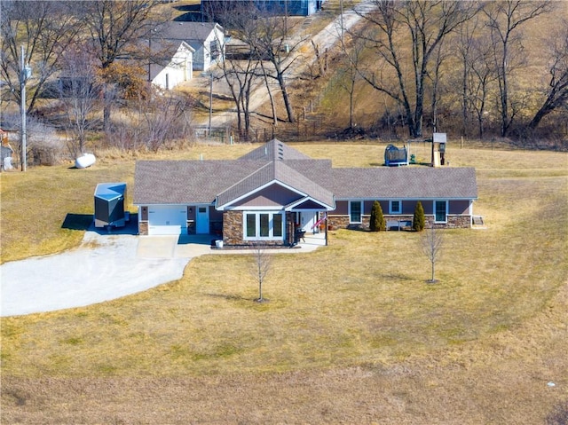 view of front facade featuring stone siding, a front lawn, and driveway