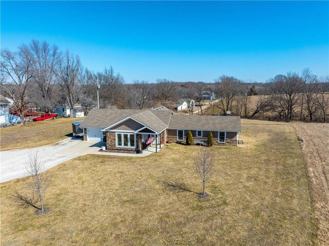 view of front of house featuring driveway, a front lawn, an attached garage, and stone siding