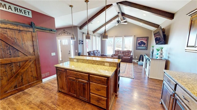 kitchen featuring dark wood-style floors, a kitchen island, vaulted ceiling with beams, and light stone countertops