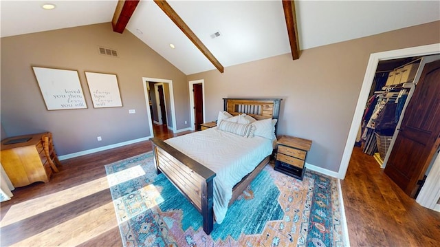 bedroom featuring visible vents, vaulted ceiling with beams, a spacious closet, and wood finished floors