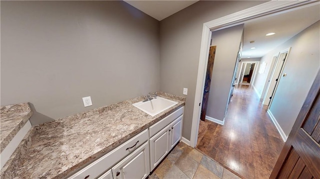 bathroom with recessed lighting, a sink, baseboards, and wood finished floors