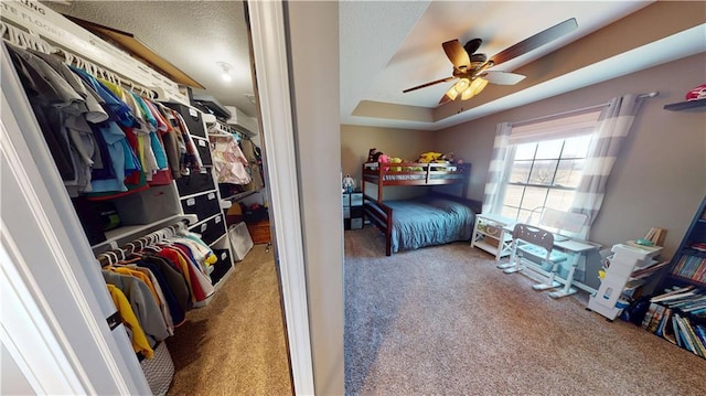 bedroom featuring carpet, a tray ceiling, and ceiling fan