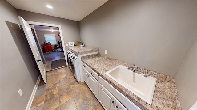 kitchen with light countertops, separate washer and dryer, a sink, and white cabinetry