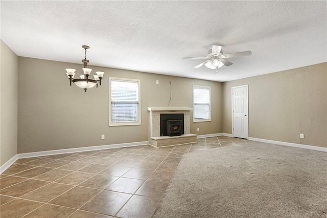 unfurnished living room with tile patterned floors, ceiling fan with notable chandelier, a textured ceiling, and baseboards