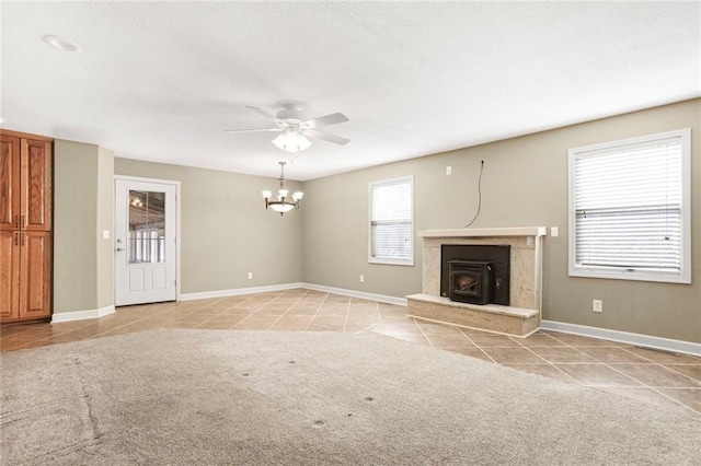 unfurnished living room featuring light tile patterned floors, baseboards, a textured ceiling, and ceiling fan with notable chandelier