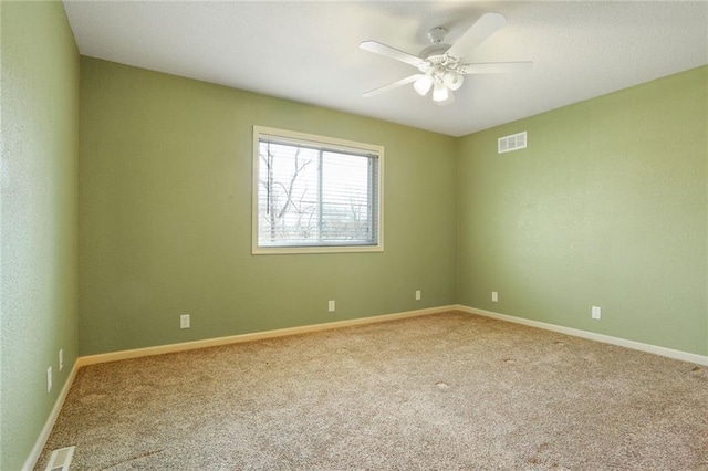 carpeted spare room featuring visible vents, baseboards, and ceiling fan