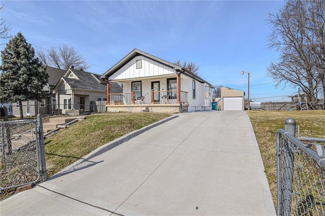 view of front of property with a front yard, a porch, an outdoor structure, a fenced front yard, and board and batten siding