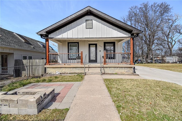 view of front of property with a porch, fence, board and batten siding, and a front lawn