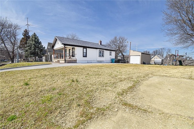 back of house featuring a porch, a lawn, and an outbuilding