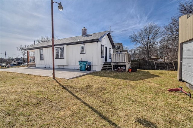 rear view of property with a shingled roof, fence, a lawn, a chimney, and a patio area