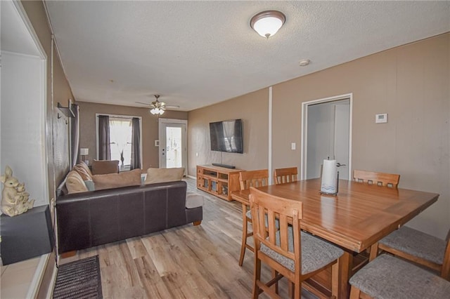 dining room with ceiling fan, a textured ceiling, and light wood-style flooring