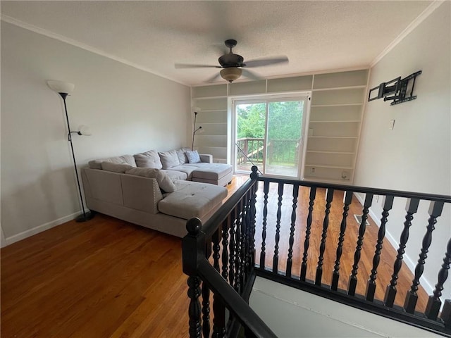 living area featuring built in features, baseboards, wood finished floors, crown molding, and a textured ceiling