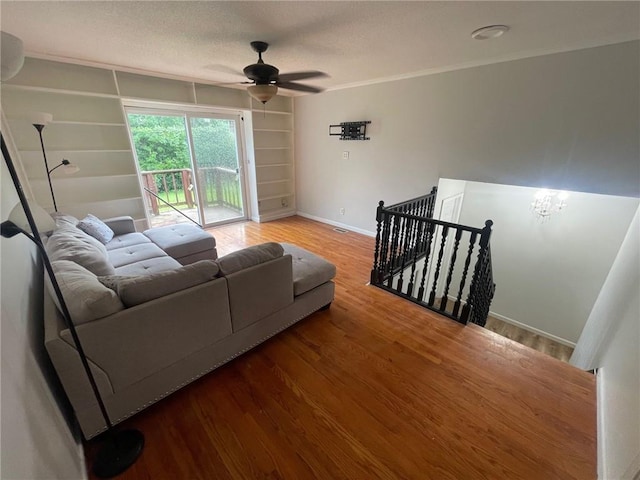 living room with wood finished floors, visible vents, baseboards, a ceiling fan, and built in features