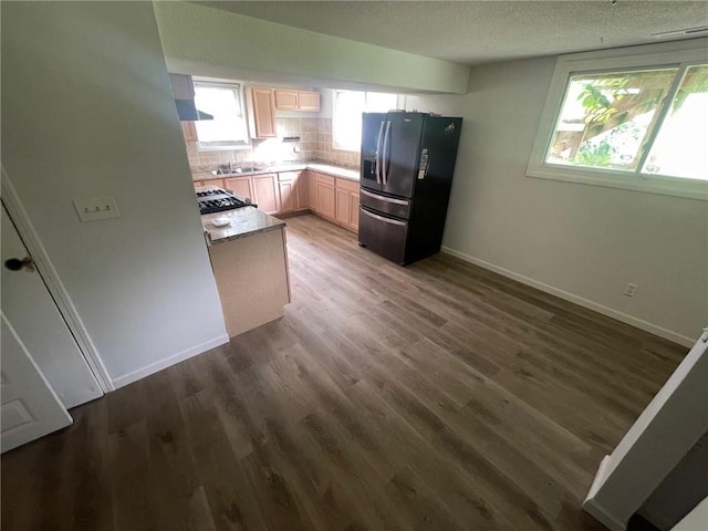 kitchen with dark wood-style floors, tasteful backsplash, a healthy amount of sunlight, and black fridge