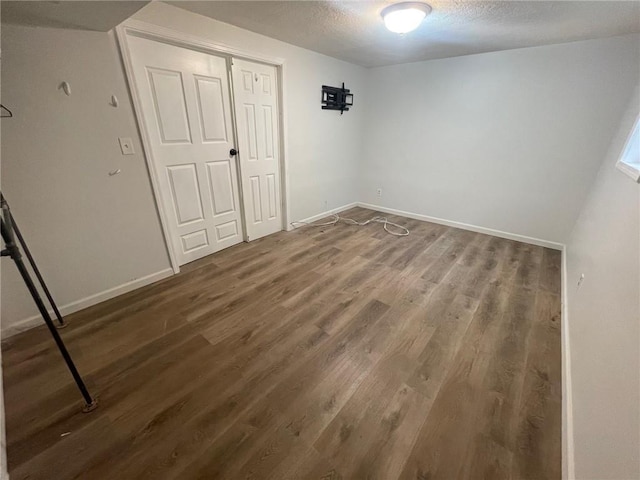 unfurnished bedroom with a textured ceiling, a closet, wood finished floors, and baseboards