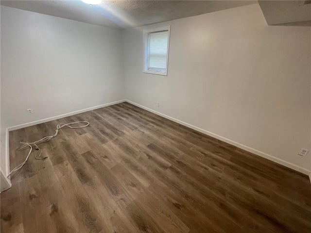 below grade area featuring dark wood-style floors, a textured ceiling, and baseboards