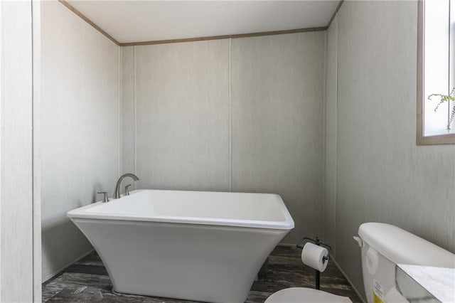 full bath with toilet, a freestanding tub, and wood finished floors