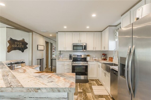 kitchen featuring white cabinets, appliances with stainless steel finishes, light countertops, and a sink