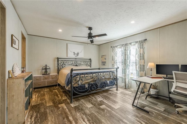 bedroom with crown molding, a textured ceiling, a decorative wall, and wood finished floors