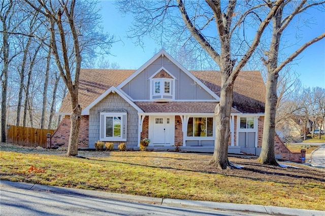 view of front of house featuring a shingled roof, fence, and a front lawn