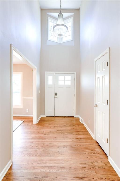 foyer entrance with light wood finished floors, a towering ceiling, and baseboards