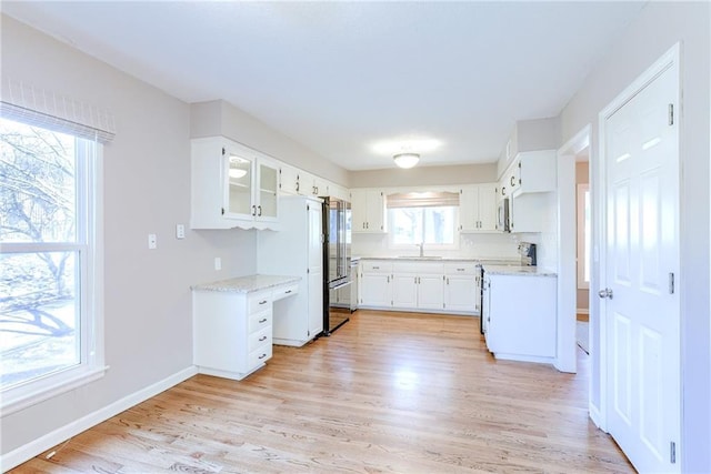 kitchen with range with electric stovetop, light wood-type flooring, white cabinetry, and baseboards