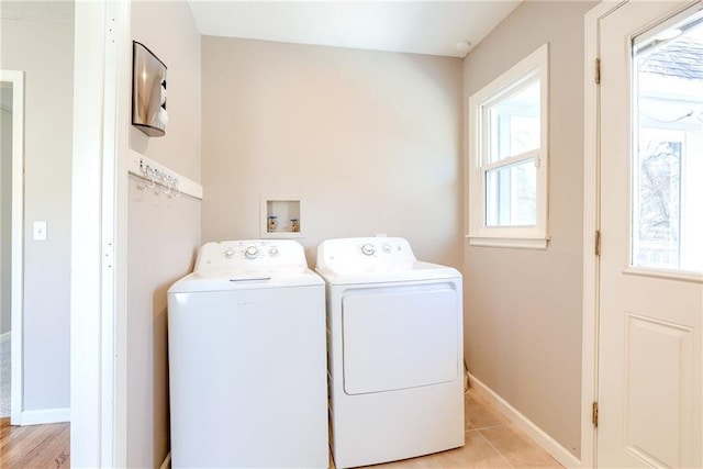 clothes washing area featuring washing machine and dryer, laundry area, light tile patterned flooring, and baseboards