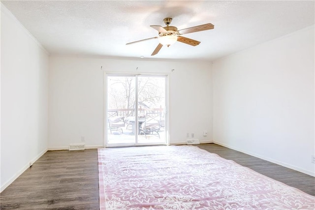 spare room with a textured ceiling, wood finished floors, visible vents, baseboards, and a ceiling fan