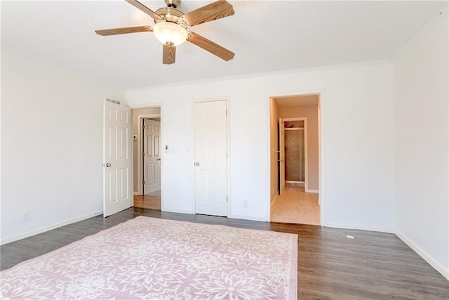 unfurnished bedroom featuring a ceiling fan, crown molding, baseboards, and dark wood-style flooring