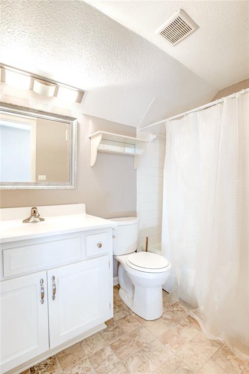 bathroom featuring a textured ceiling, toilet, vanity, visible vents, and a shower with curtain