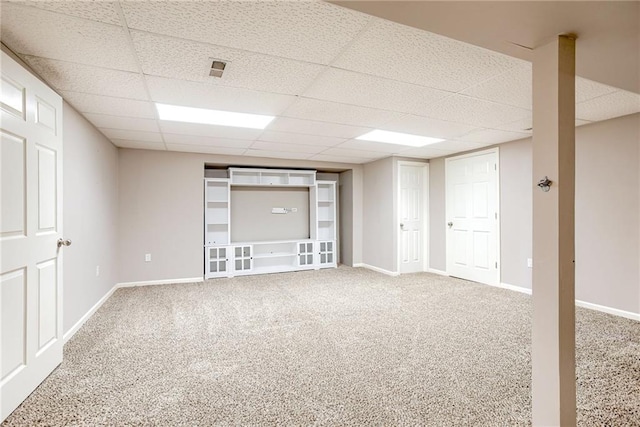 finished below grade area featuring carpet floors, a drop ceiling, and baseboards