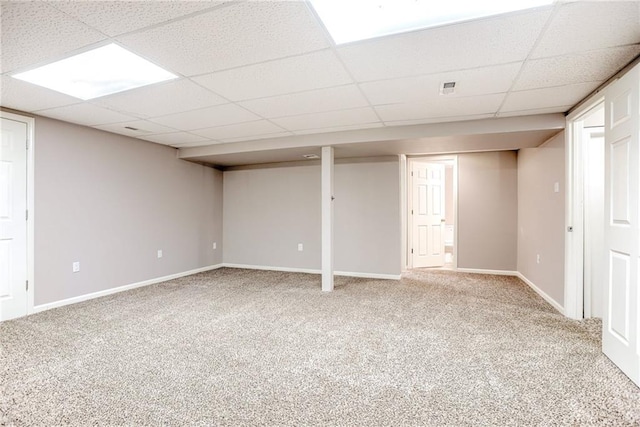 finished basement with baseboards, a drop ceiling, and carpet flooring