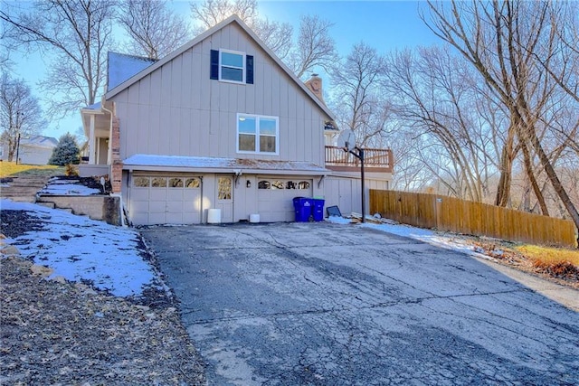 view of property exterior featuring a garage, driveway, a chimney, and fence