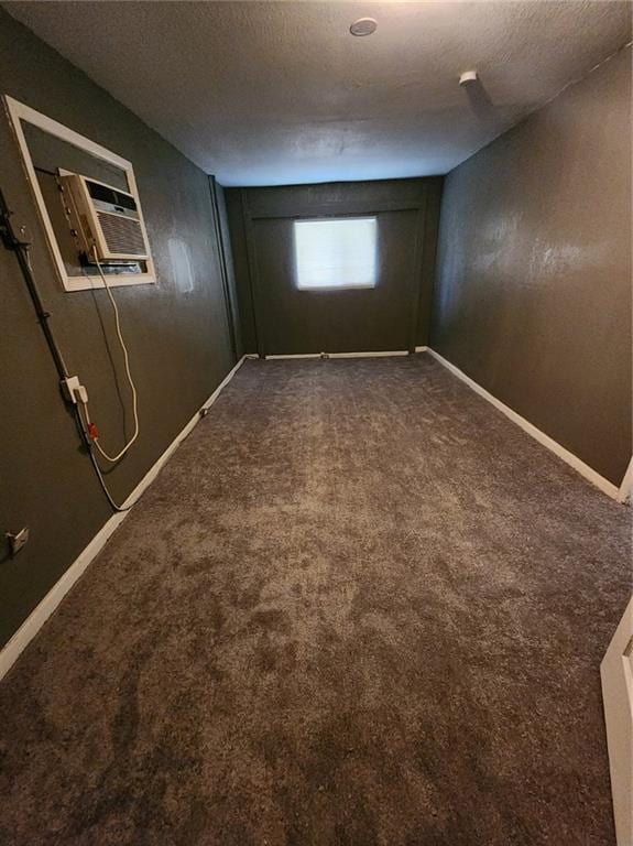 basement featuring dark colored carpet, a textured ceiling, and baseboards