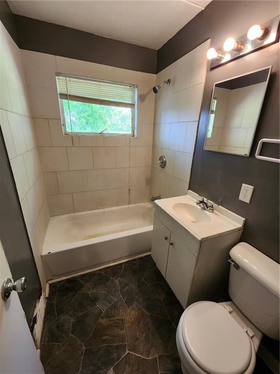 full bath featuring toilet, vanity, and bathing tub / shower combination