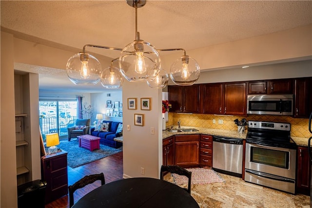 kitchen with a textured ceiling, appliances with stainless steel finishes, backsplash, and a sink