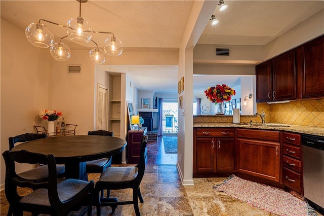 kitchen featuring a sink, visible vents, dishwasher, tasteful backsplash, and stone tile flooring