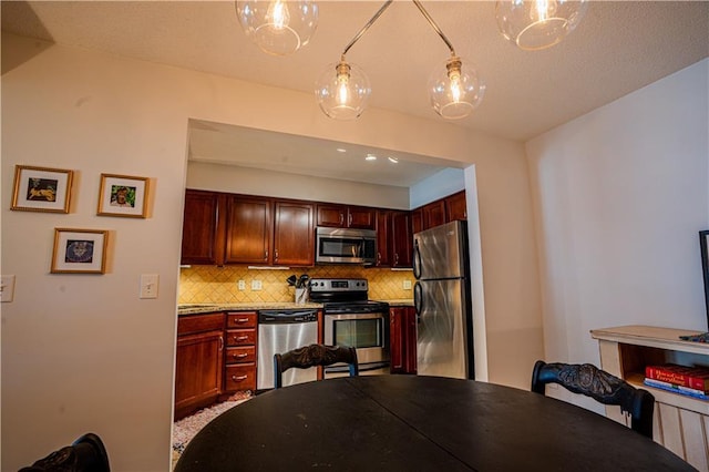 kitchen with tasteful backsplash, stainless steel appliances, light countertops, and decorative light fixtures