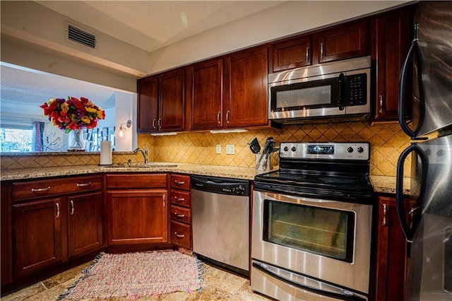 kitchen featuring appliances with stainless steel finishes, a sink, visible vents, and light stone countertops