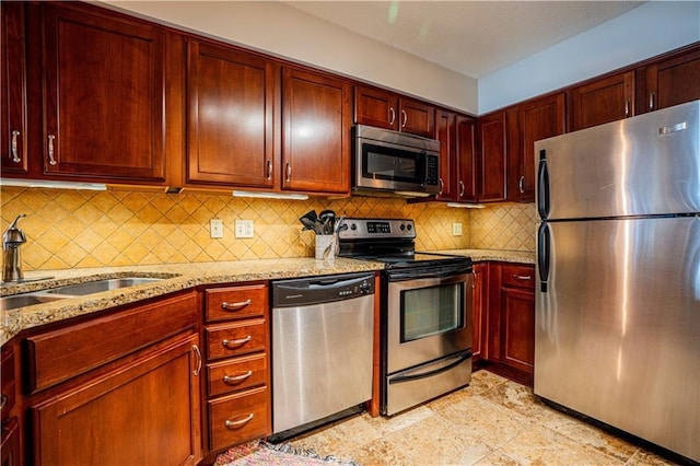 kitchen with reddish brown cabinets, tasteful backsplash, light stone counters, stainless steel appliances, and a sink