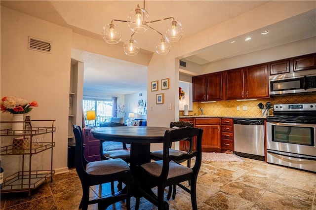 kitchen featuring a notable chandelier, tasteful backsplash, visible vents, appliances with stainless steel finishes, and baseboards