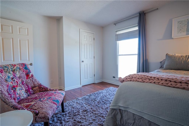 bedroom with a textured ceiling, baseboards, and wood finished floors